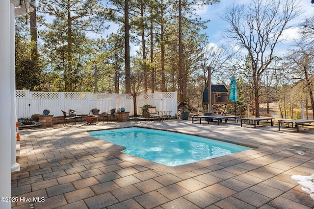 view of pool featuring a fenced in pool, a patio area, a fenced backyard, an outdoor structure, and a fire pit