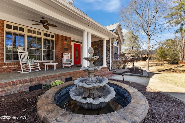 entrance to property with a porch, a ceiling fan, and brick siding