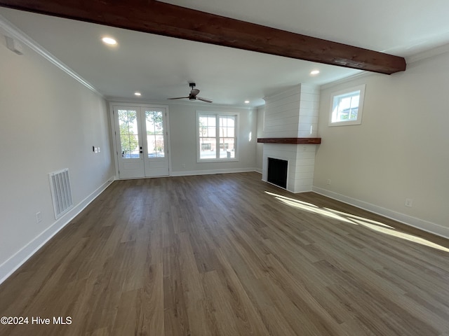 unfurnished living room with a large fireplace, wood finished floors, visible vents, baseboards, and beamed ceiling