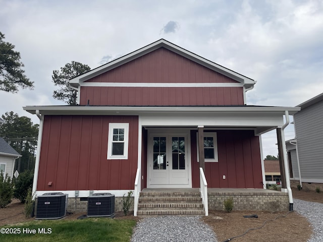 view of front of house featuring covered porch, french doors, board and batten siding, and cooling unit