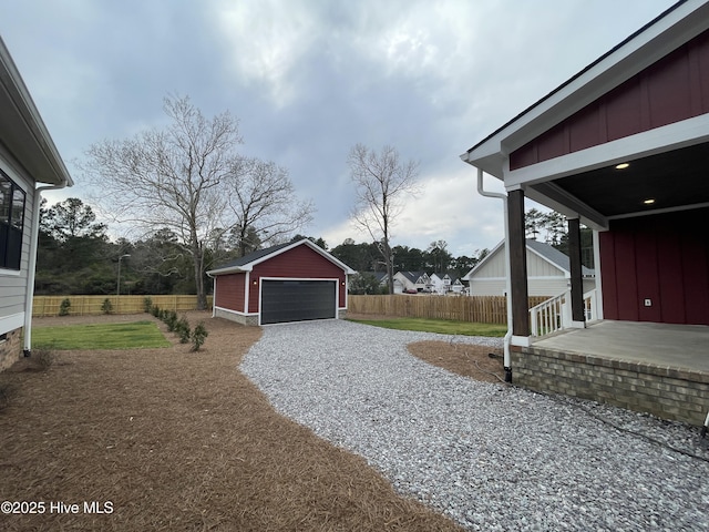 view of yard with a garage, fence, and an outbuilding