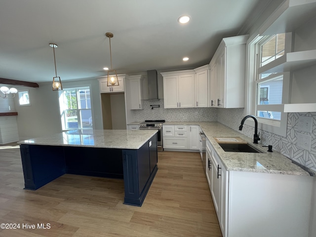 kitchen with stainless steel electric range oven, a center island, wall chimney range hood, white cabinetry, and a sink