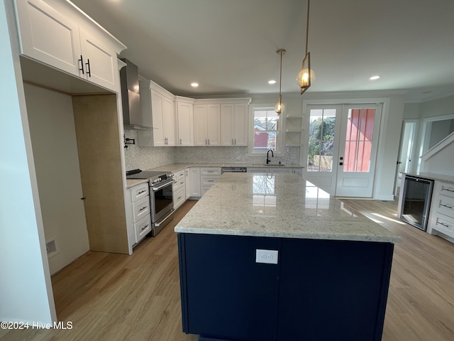 kitchen featuring backsplash, appliances with stainless steel finishes, a sink, wall chimney range hood, and beverage cooler