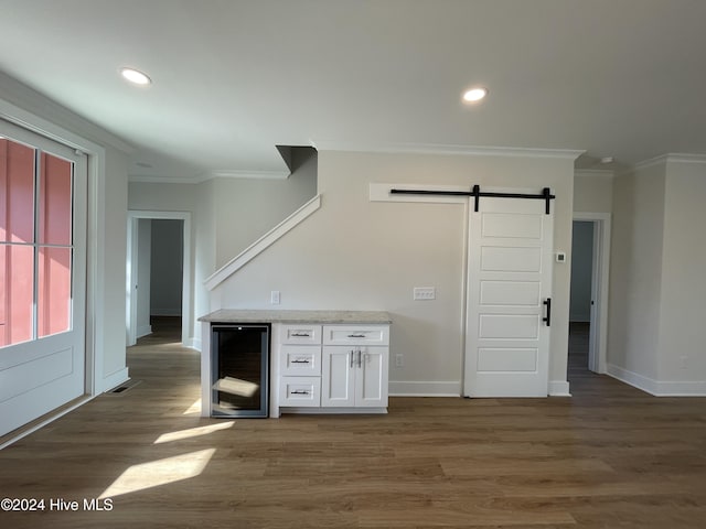 bar with wine cooler, a barn door, wood finished floors, and crown molding