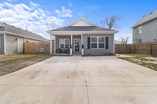 bungalow with covered porch, a shingled roof, and fence