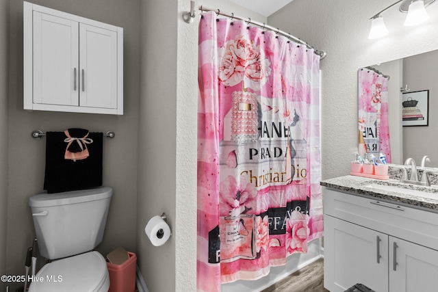 bathroom featuring toilet, wood finished floors, a shower with shower curtain, and vanity