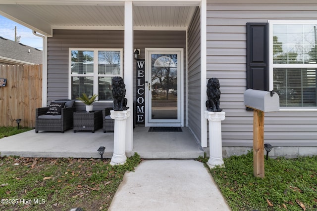 doorway to property featuring a porch and fence