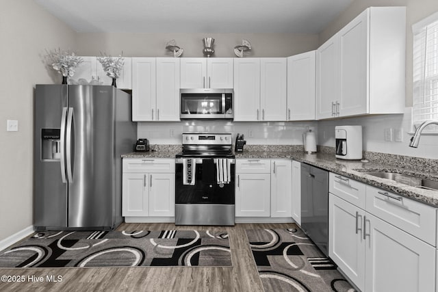 kitchen with white cabinetry, appliances with stainless steel finishes, backsplash, and a sink