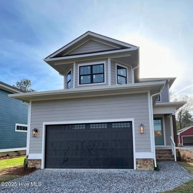 view of front of home with an attached garage and gravel driveway