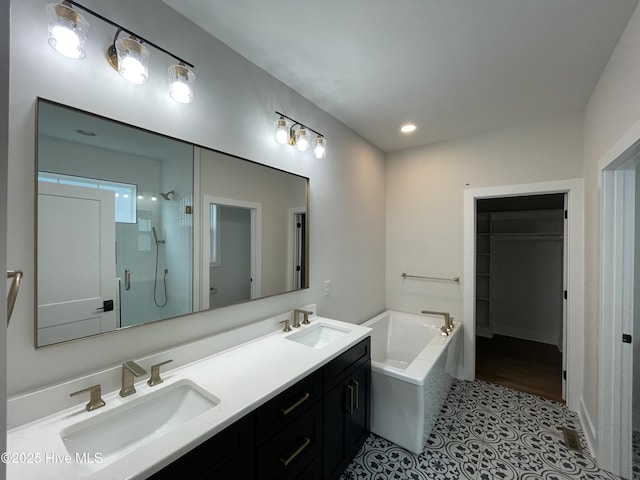 bathroom with a bath, a shower stall, double vanity, and a sink