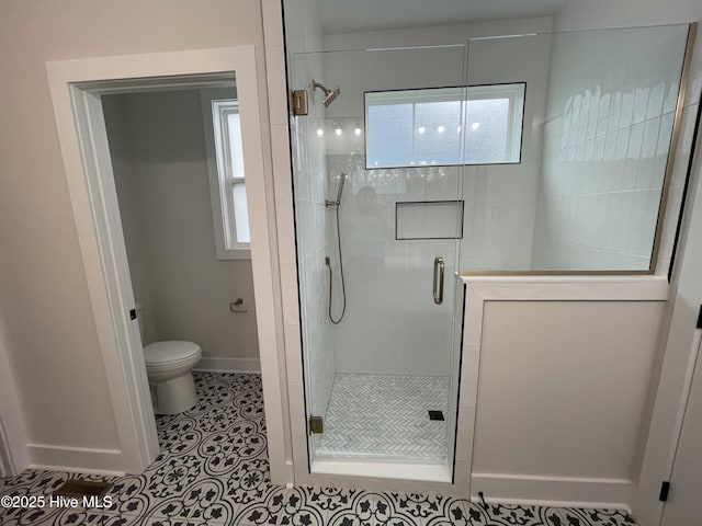 bathroom featuring a stall shower, baseboards, toilet, and tile patterned floors