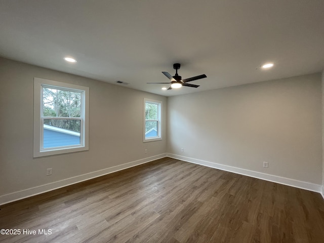 empty room with dark wood-style floors, recessed lighting, visible vents, and baseboards