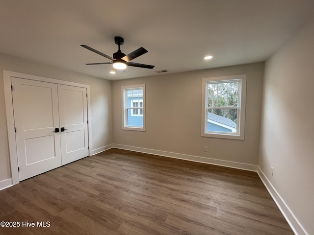 unfurnished bedroom with dark wood-type flooring, visible vents, baseboards, and multiple windows