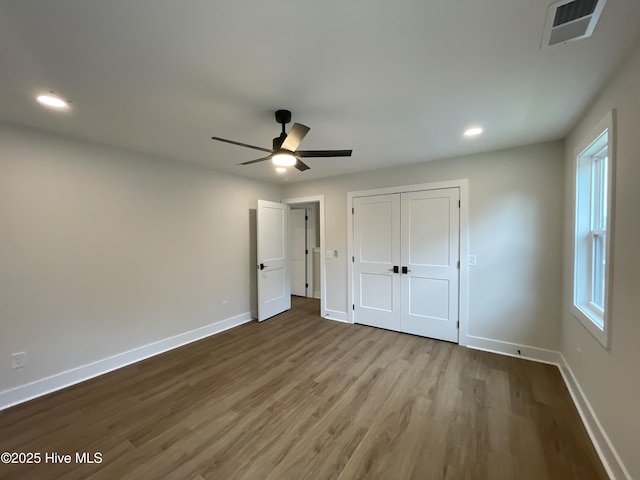 unfurnished bedroom with recessed lighting, a closet, visible vents, wood finished floors, and baseboards