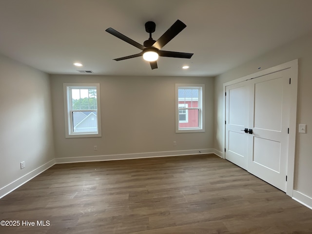 unfurnished bedroom with baseboards, visible vents, multiple windows, and wood finished floors