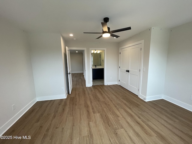 unfurnished bedroom featuring connected bathroom, recessed lighting, wood finished floors, baseboards, and a closet