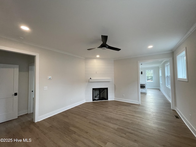 unfurnished living room featuring dark wood-style floors, a fireplace, crown molding, recessed lighting, and baseboards