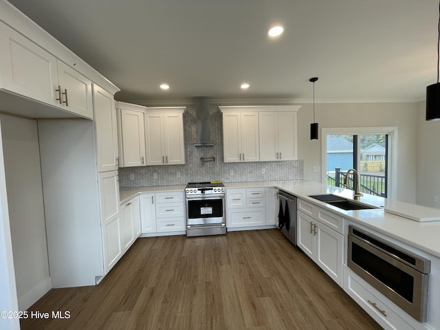 kitchen featuring tasteful backsplash, appliances with stainless steel finishes, crown molding, wall chimney range hood, and a sink