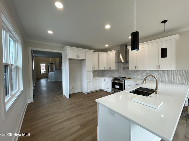 kitchen with stainless steel electric range oven, ornamental molding, a sink, a peninsula, and wall chimney exhaust hood