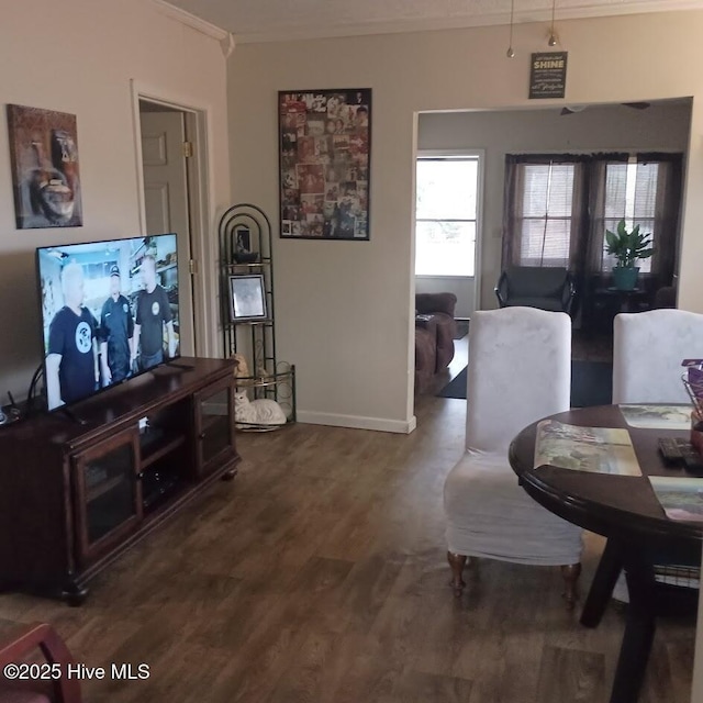 living area featuring baseboards, crown molding, and wood finished floors