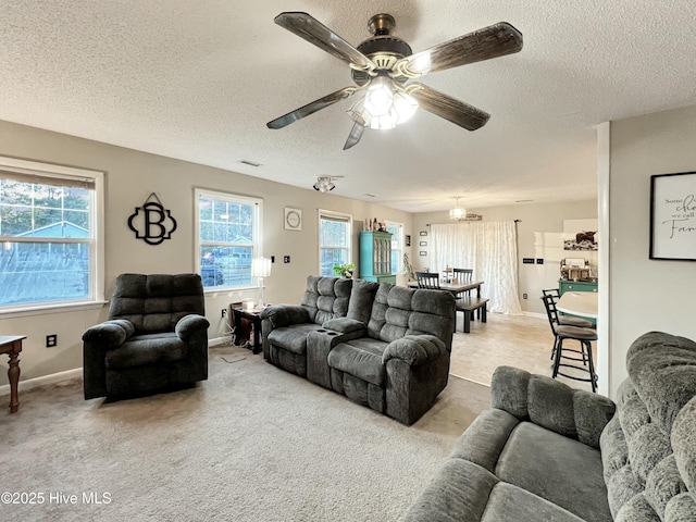 living area with carpet, plenty of natural light, visible vents, and a ceiling fan