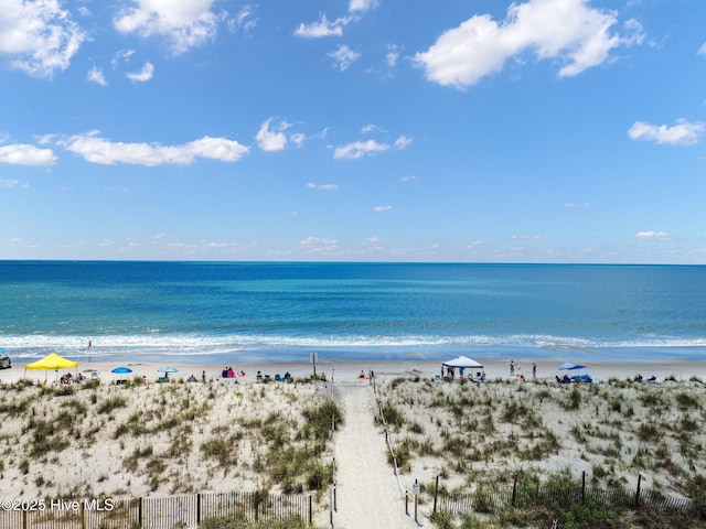 property view of water with fence and a beach view