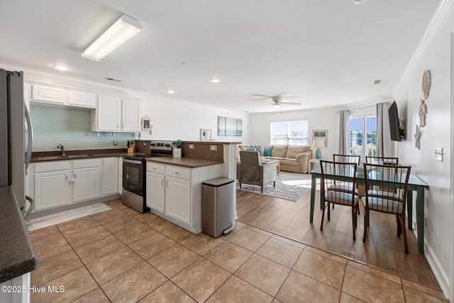 kitchen with stainless steel appliances, dark countertops, a peninsula, and white cabinetry