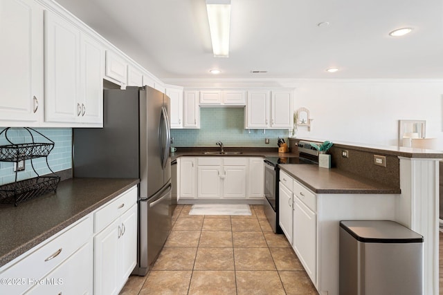 kitchen with a peninsula, appliances with stainless steel finishes, dark countertops, and white cabinetry