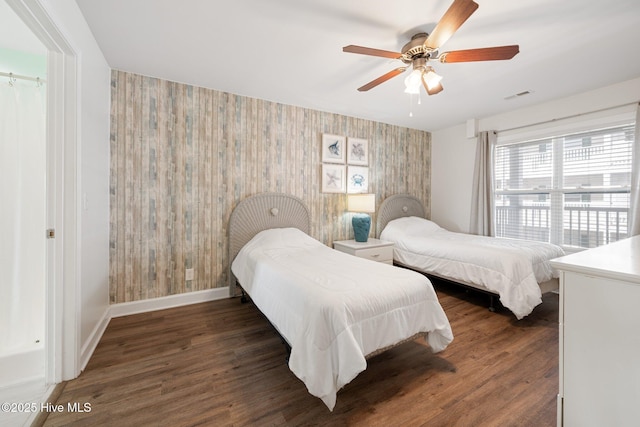 bedroom featuring visible vents, a ceiling fan, wood finished floors, baseboards, and wallpapered walls