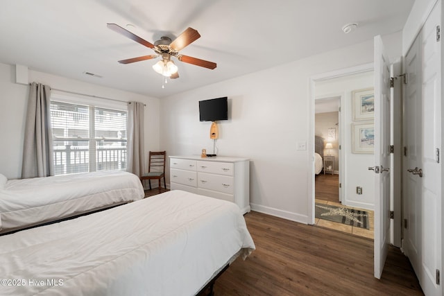 bedroom with ceiling fan, visible vents, baseboards, and dark wood-type flooring