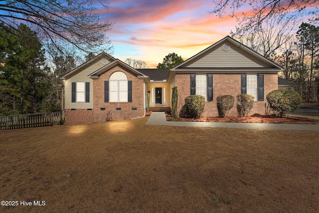 ranch-style house featuring a front yard, fence, brick siding, and crawl space