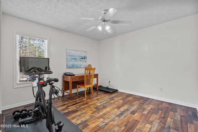 exercise area featuring baseboards, a textured ceiling, a ceiling fan, and wood finished floors