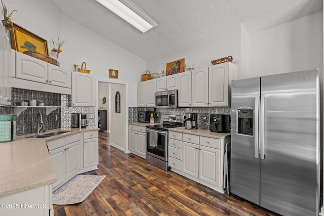 kitchen with white cabinetry, stainless steel appliances, light countertops, and a sink