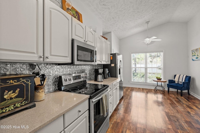 kitchen featuring dark wood finished floors, appliances with stainless steel finishes, white cabinets, decorative backsplash, and lofted ceiling