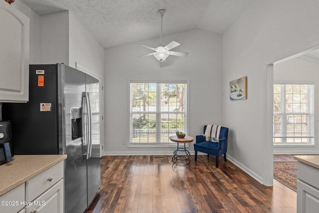 kitchen featuring dark wood finished floors, light countertops, lofted ceiling, stainless steel refrigerator with ice dispenser, and white cabinetry