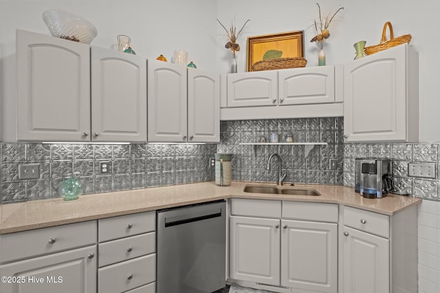 kitchen featuring dishwasher, tasteful backsplash, white cabinetry, and a sink