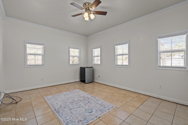 empty room with crown molding, light tile patterned floors, a ceiling fan, and baseboards