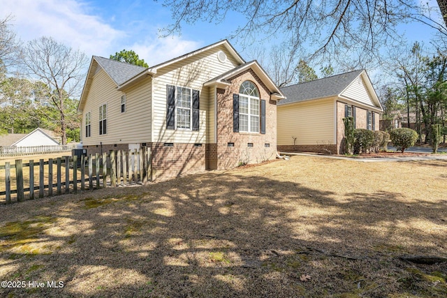 view of side of home with crawl space, brick siding, roof with shingles, and fence