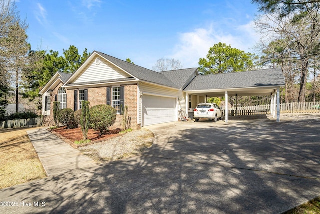 ranch-style home with brick siding, an attached carport, fence, concrete driveway, and an attached garage