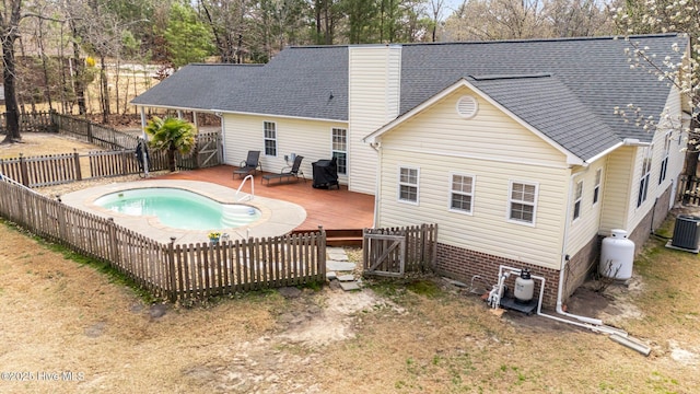 back of house featuring a deck, a fenced backyard, cooling unit, roof with shingles, and a chimney