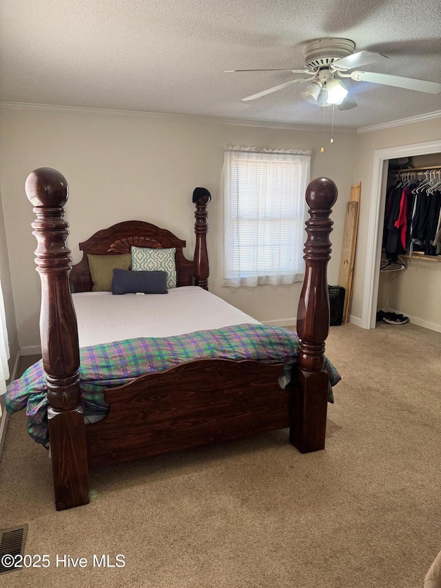 carpeted bedroom with a textured ceiling, ceiling fan, visible vents, and crown molding