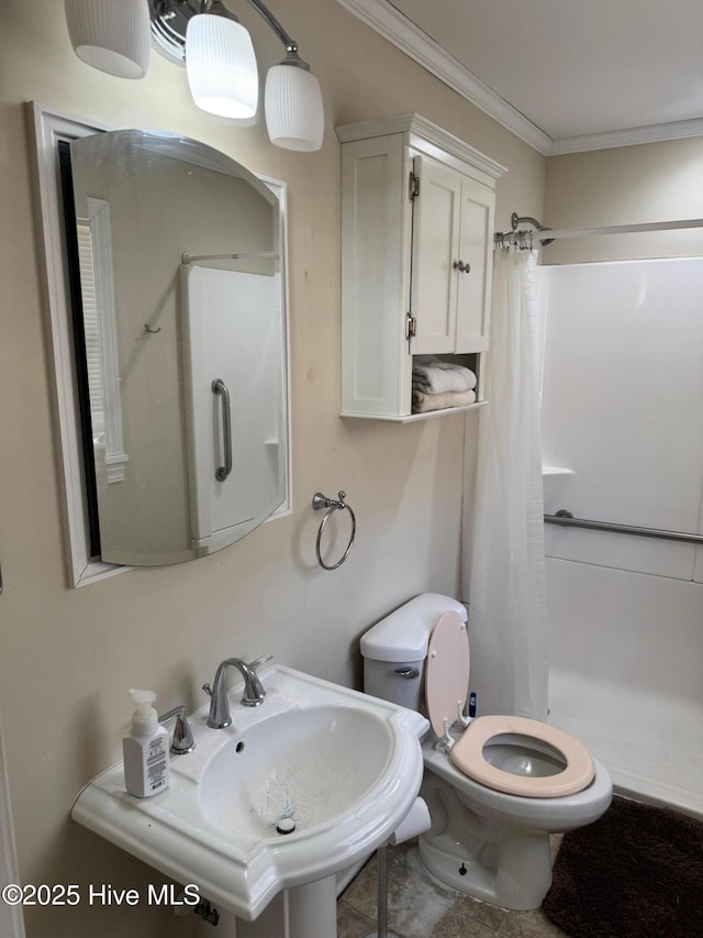 bathroom with a stall shower, a sink, toilet, and crown molding