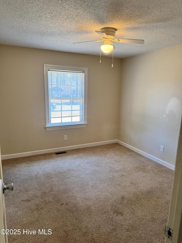 unfurnished room with carpet floors, a ceiling fan, visible vents, and baseboards