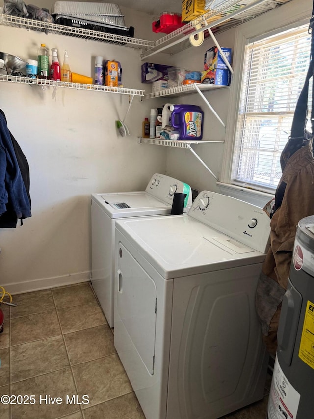 clothes washing area with electric water heater, light tile patterned flooring, laundry area, independent washer and dryer, and baseboards