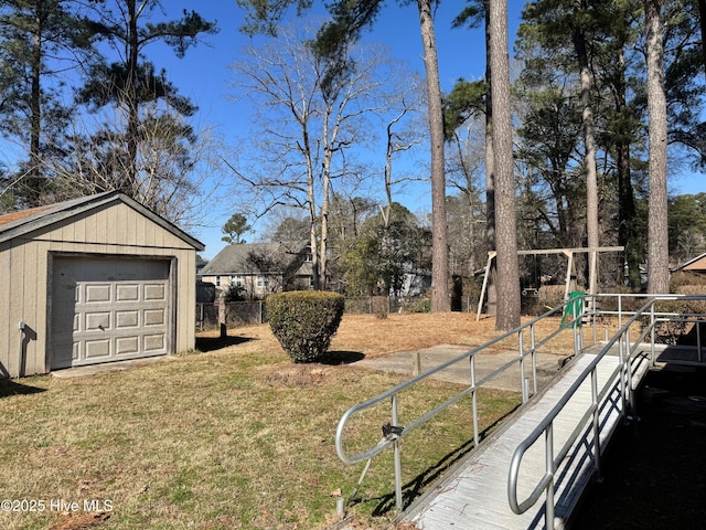 view of yard featuring a garage, an outdoor structure, driveway, and fence