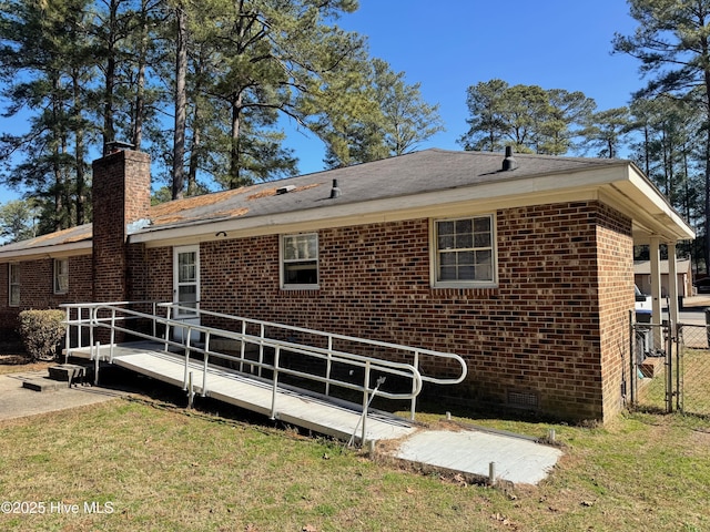 back of property featuring a lawn, a chimney, crawl space, fence, and brick siding