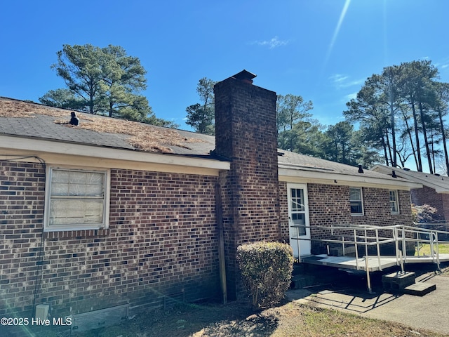 back of house featuring brick siding and a chimney