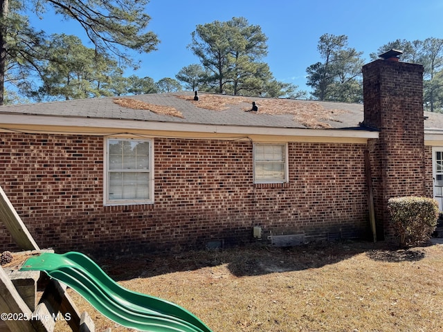 view of side of property featuring crawl space, a chimney, and brick siding