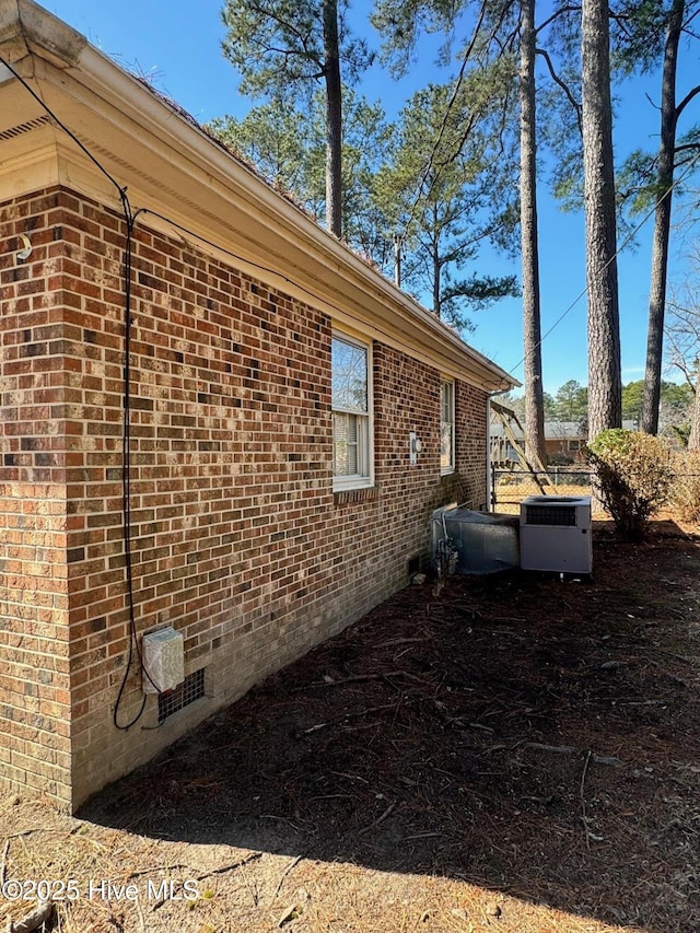 view of home's exterior with central AC, brick siding, and crawl space