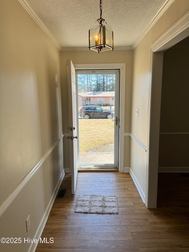 entryway featuring ornamental molding, a textured ceiling, baseboards, and wood finished floors